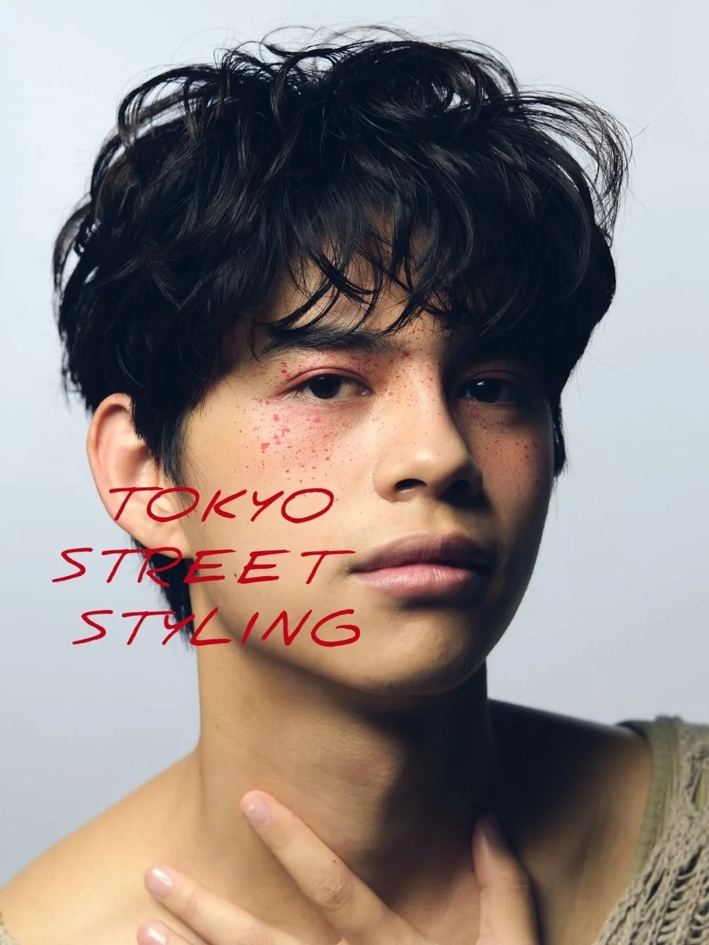 個性的な赤色のメイクとパーマ風のヘアスタイルをした若い男性のポートレート