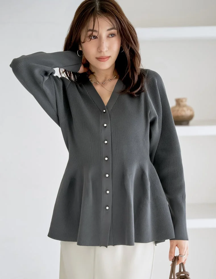 暗いグレーのリブニットカーディガンと白いパンツを着用した女性のポートレート