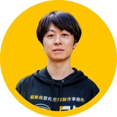 「超絶仮想的空間制作事務所」と書かれたパーカーを着た男性のポートレート