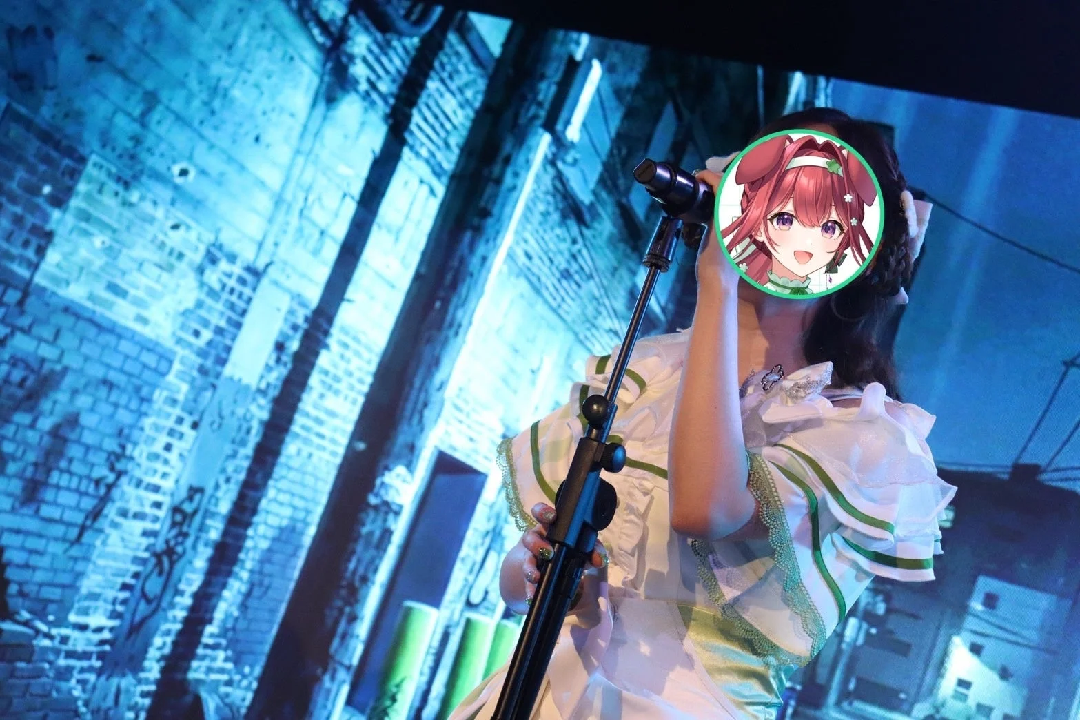 白と緑の衣装を着た人物がマイクを持ち、ステージ上でパフォーマンスしている様子