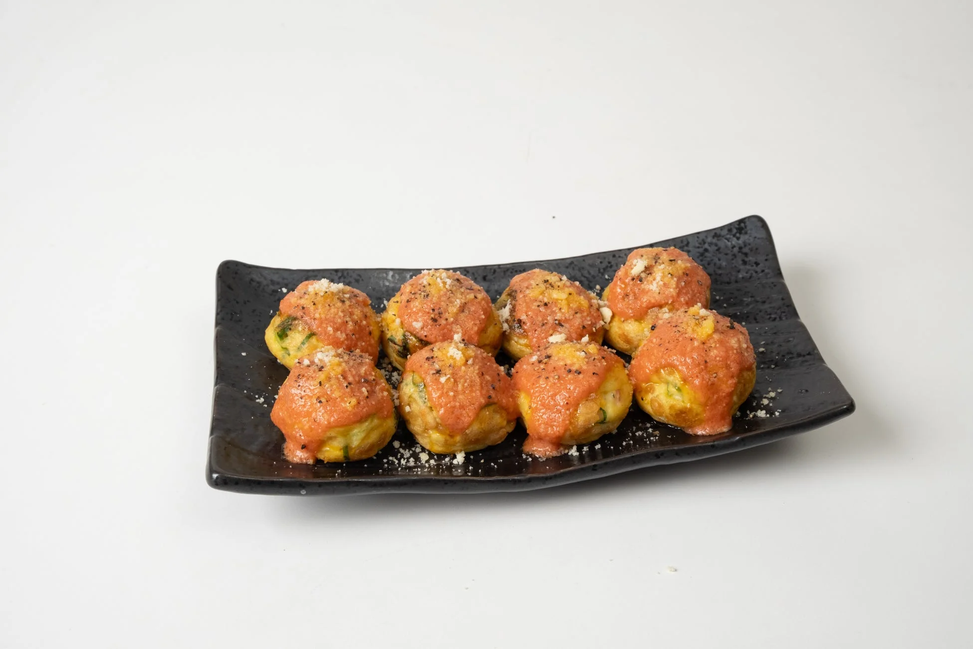 黒い皿に盛られたバター香る博多明太たこ焼