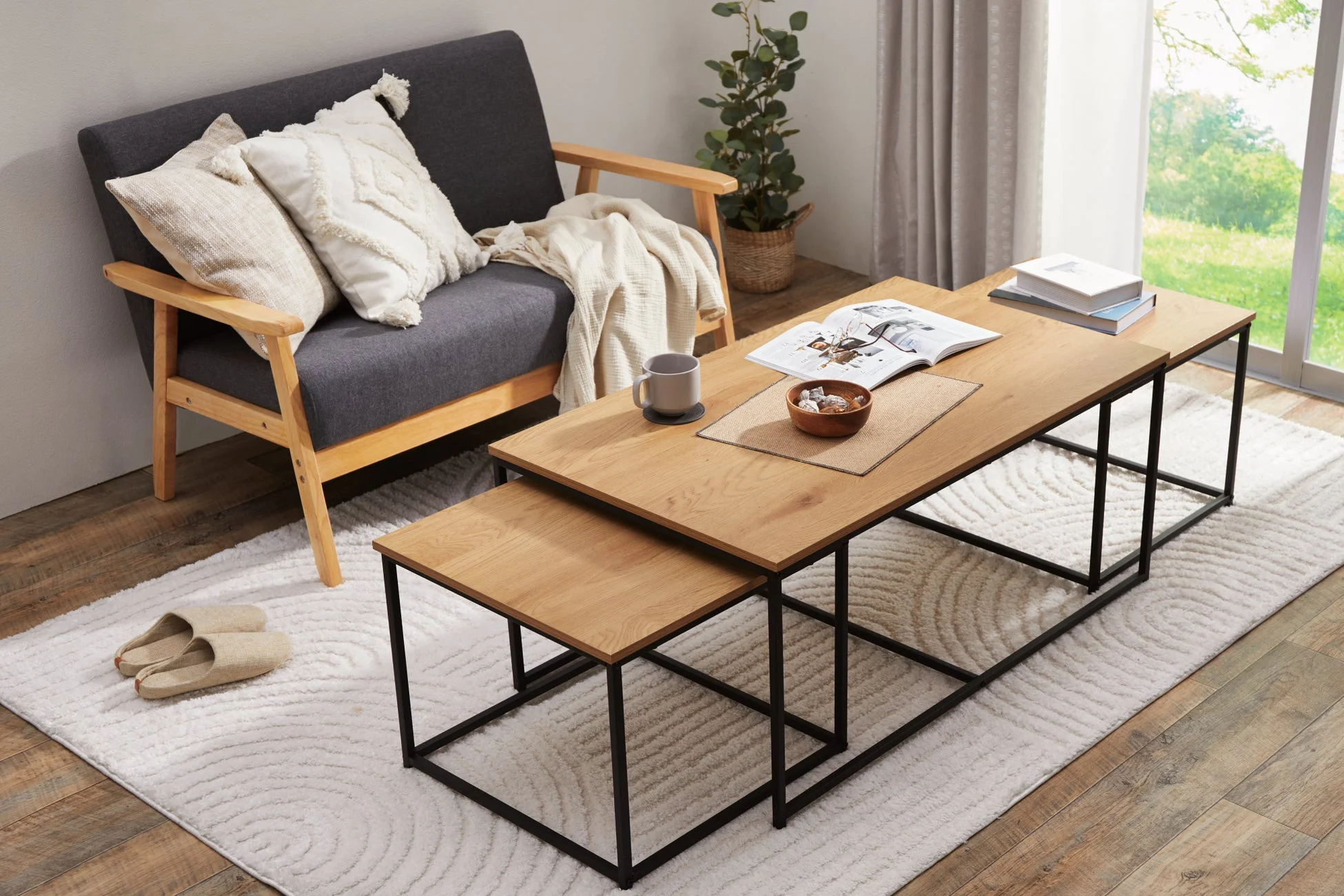 グレーのソファと木製天板のネストコーヒーテーブルが配置されたリビングルーム