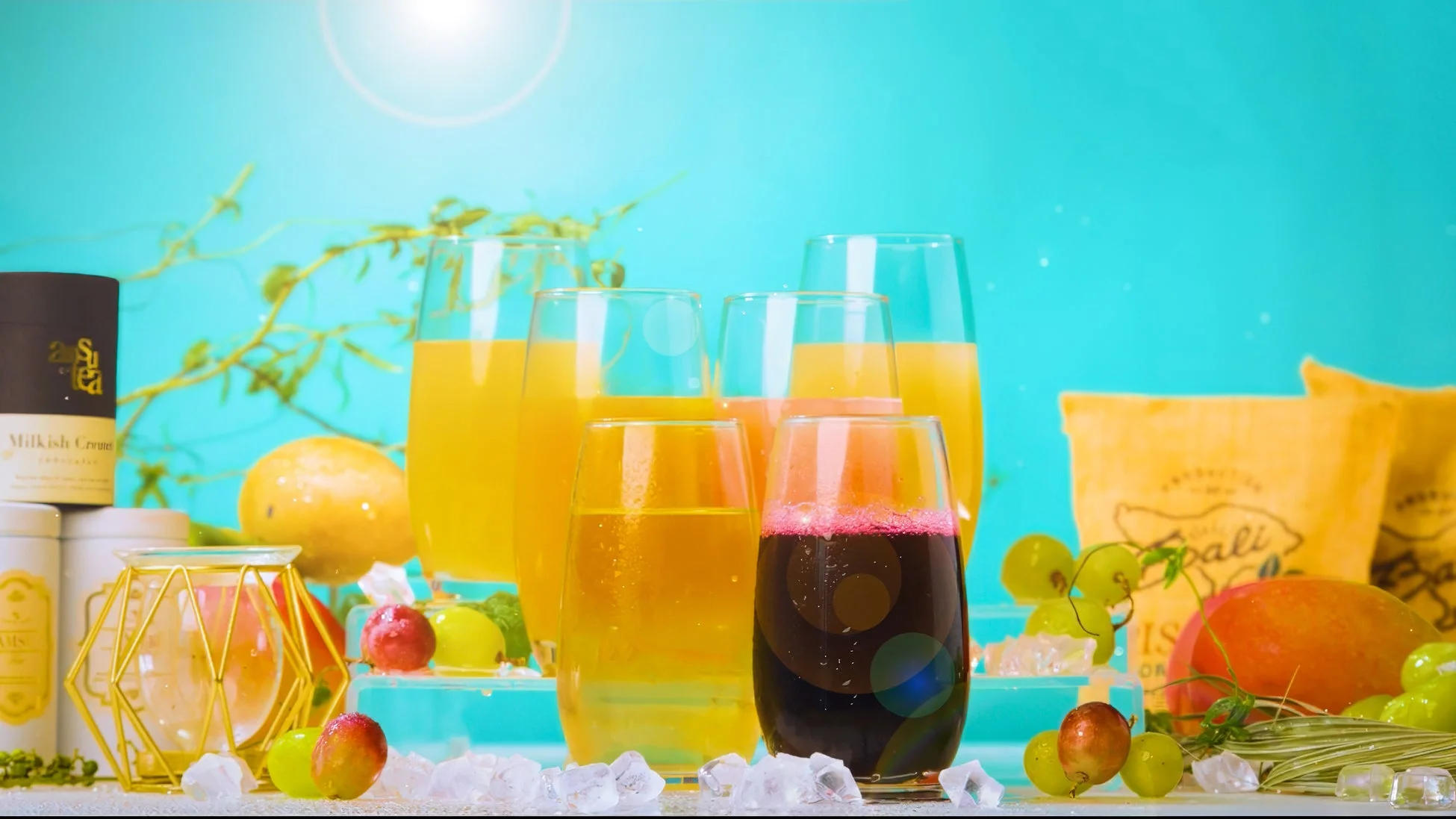 様々な色のフルーツジュースが入ったグラスが並び、マンゴーやブドウ、氷が添えられています