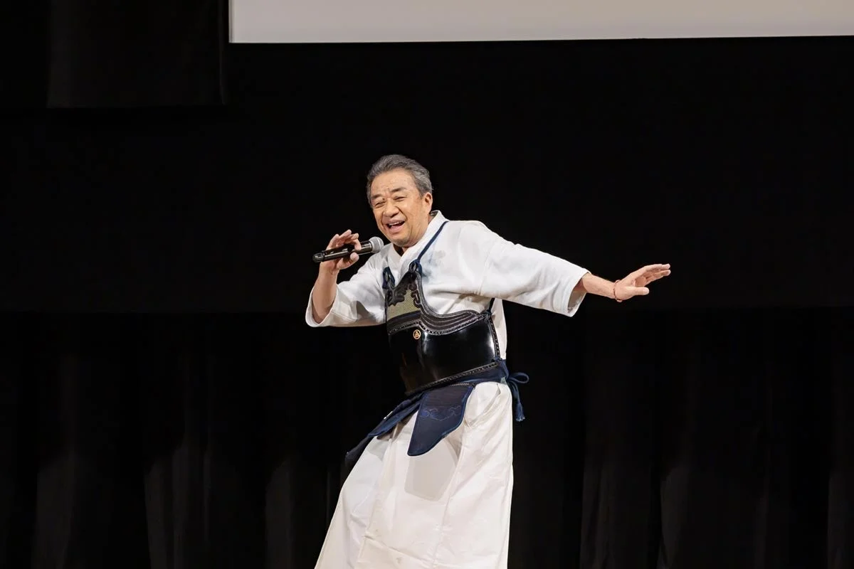 剣道着姿でマイクを手に歌唱またはパフォーマンスをする男性