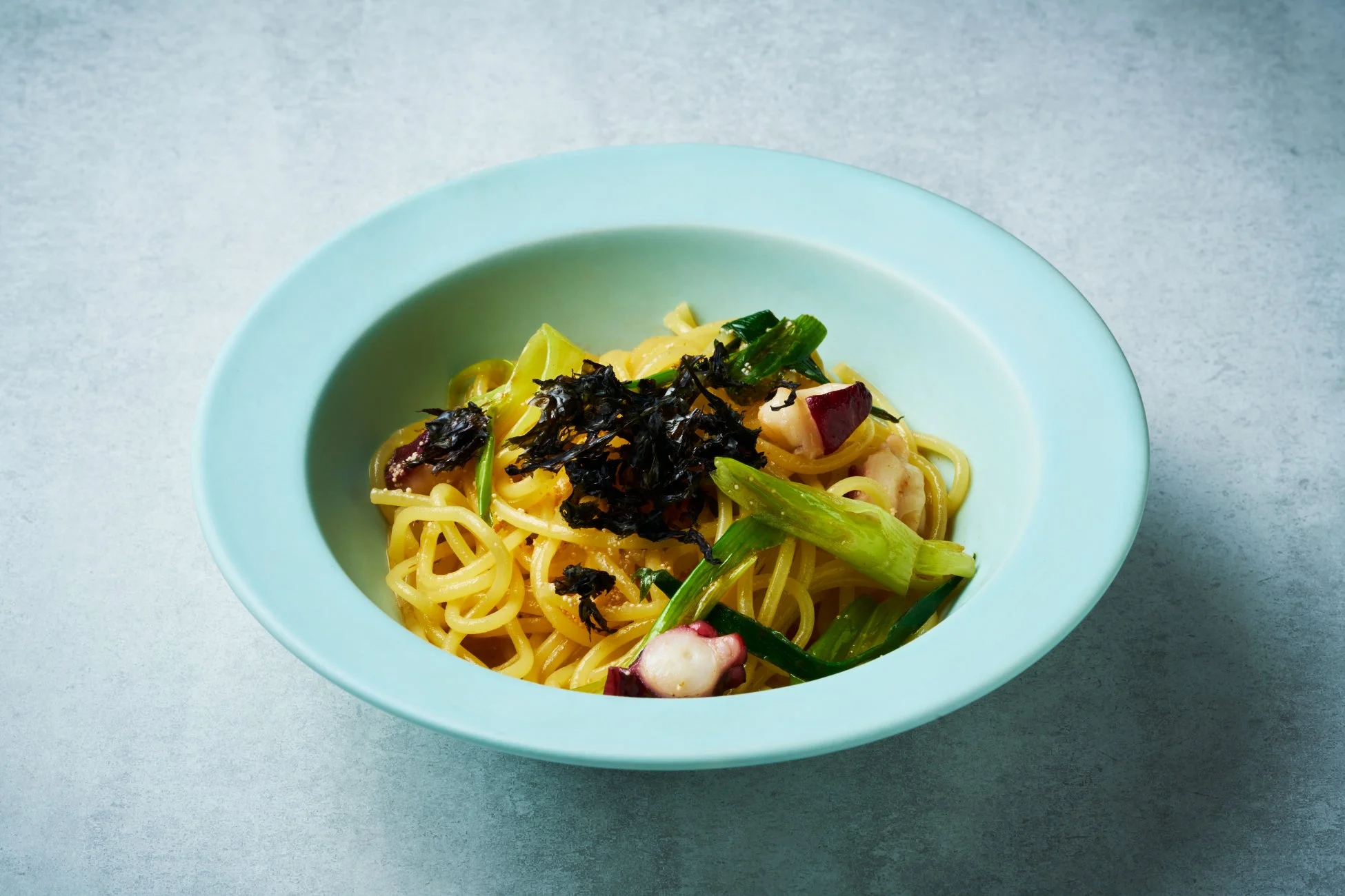 タコと緑色の野菜、刻み海苔がたっぷり乗った和風パスタ