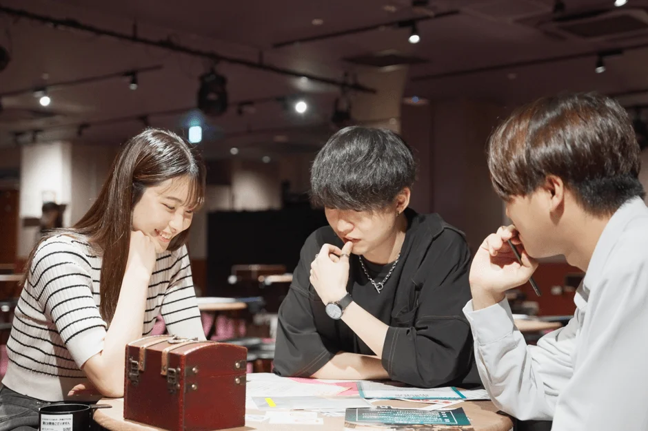 若者たちがテーブルを囲んで謎解きに挑む様子