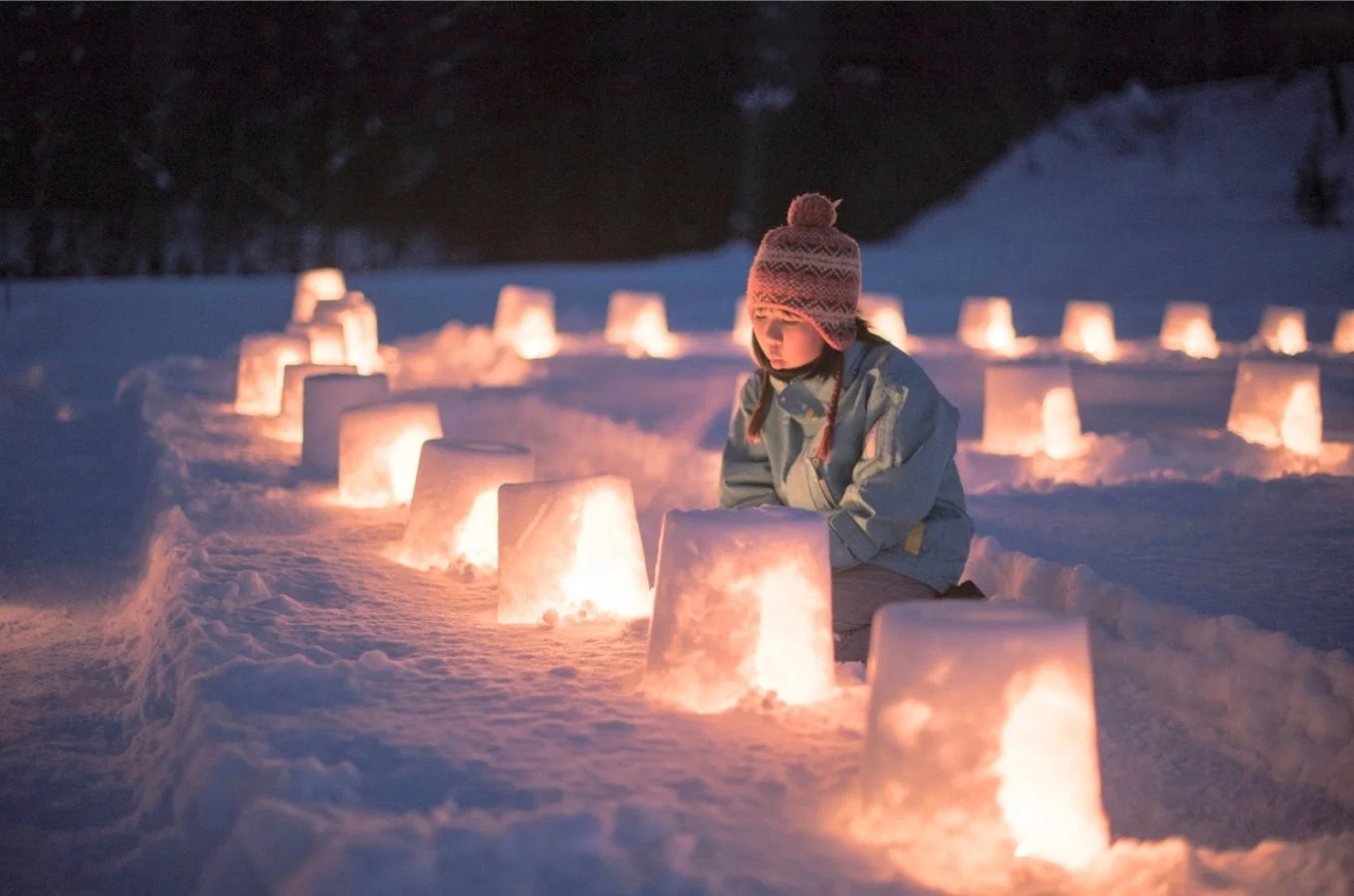 雪灯籠に囲まれて座る子供