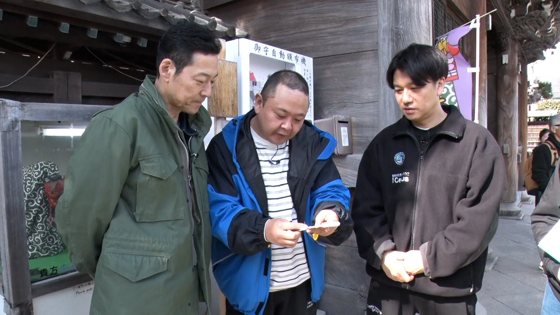 寺社でおみくじを引く男性たち