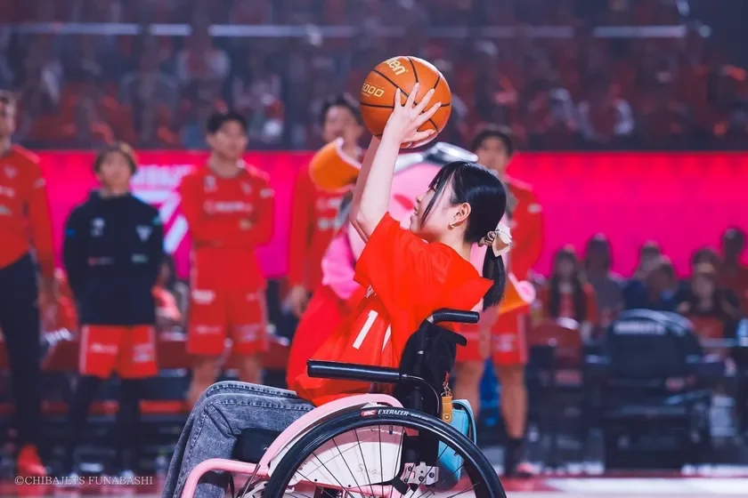 車椅子に乗った小雪さんがバスケットボールを構える様子