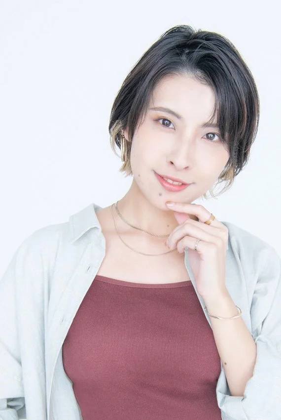 ショートヘアの女性が笑顔でポーズをとっています