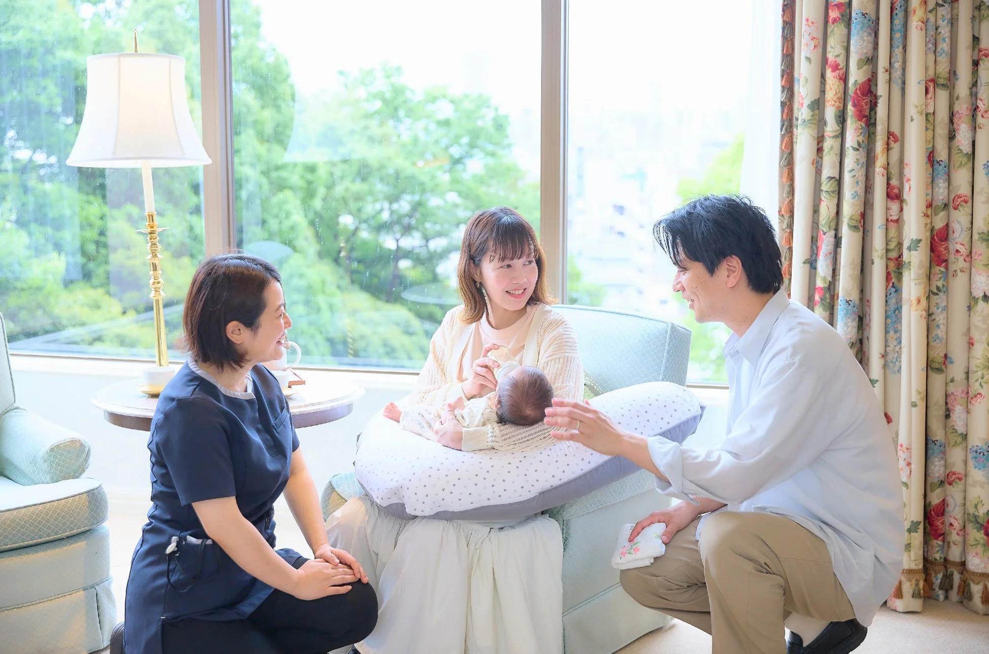 新生児を抱く夫婦と助産師らしき人物が相談している様子