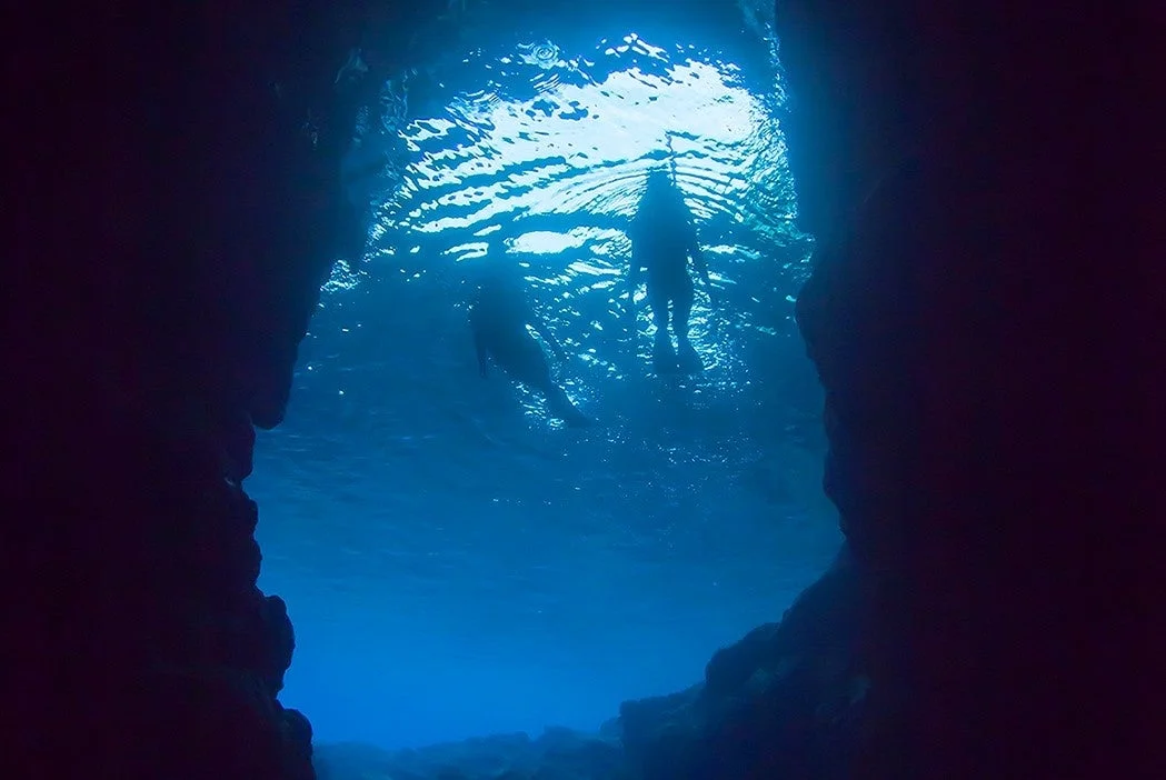 青く輝く水中洞窟のダイバー