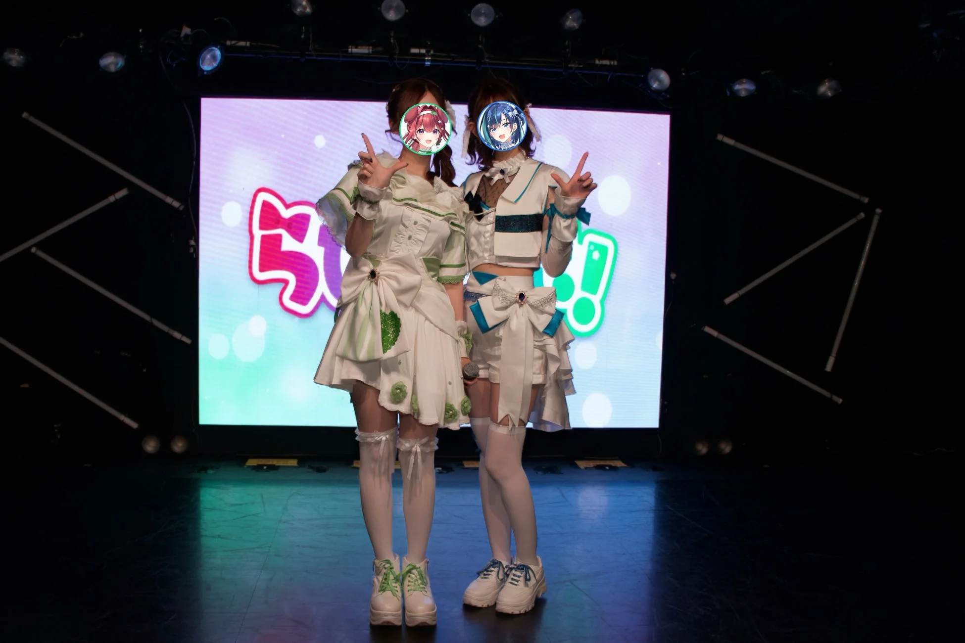 アイドルがステージ上でVサインをしてポーズをとっている様子