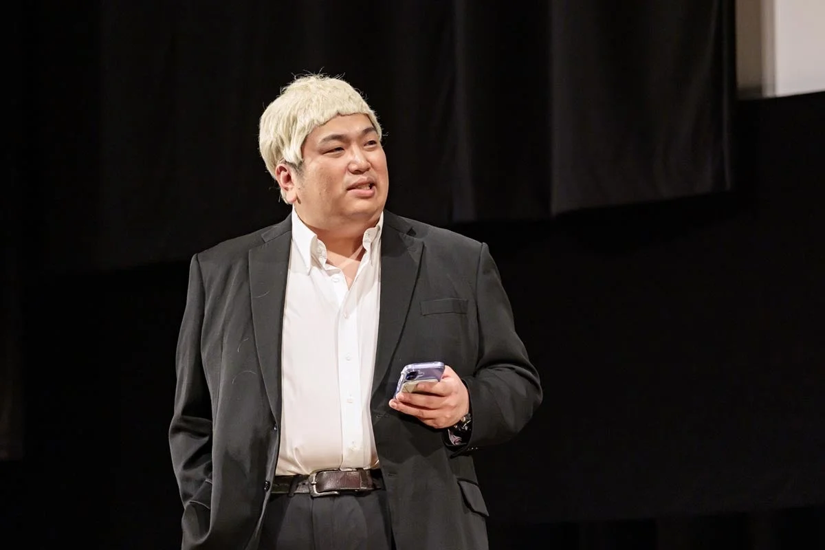 金髪ウィッグを被り、スマートフォンを手に持つ男性