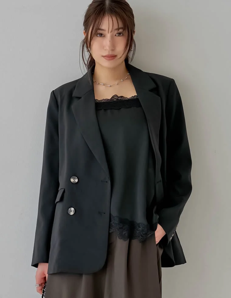 黒のオーバーサイズブレザーとレーストリムのキャミソール、ダークブラウンのワイドパンツを着用した女性のポートレート