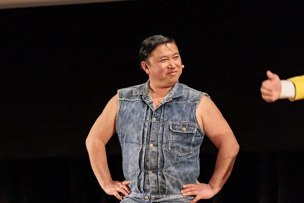 デニムベストを着て笑顔でポーズをとる男性