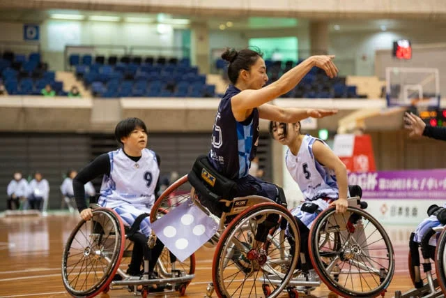 車椅子バスケットボールの試合中、選手たちがコート上でプレイしている様子