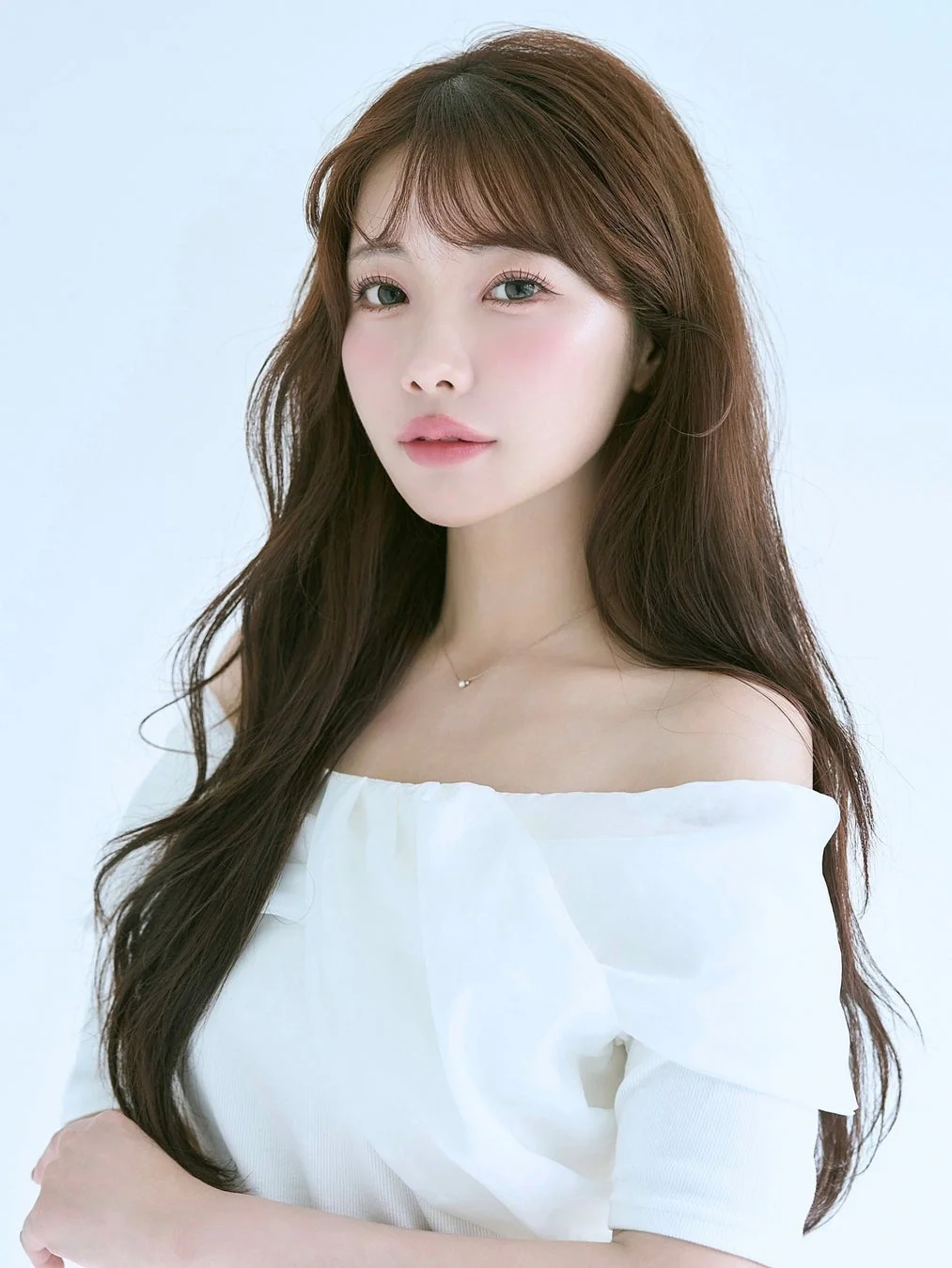 白いオフショルダーのトップスを着用した、長い茶髪の若い女性のポートレート