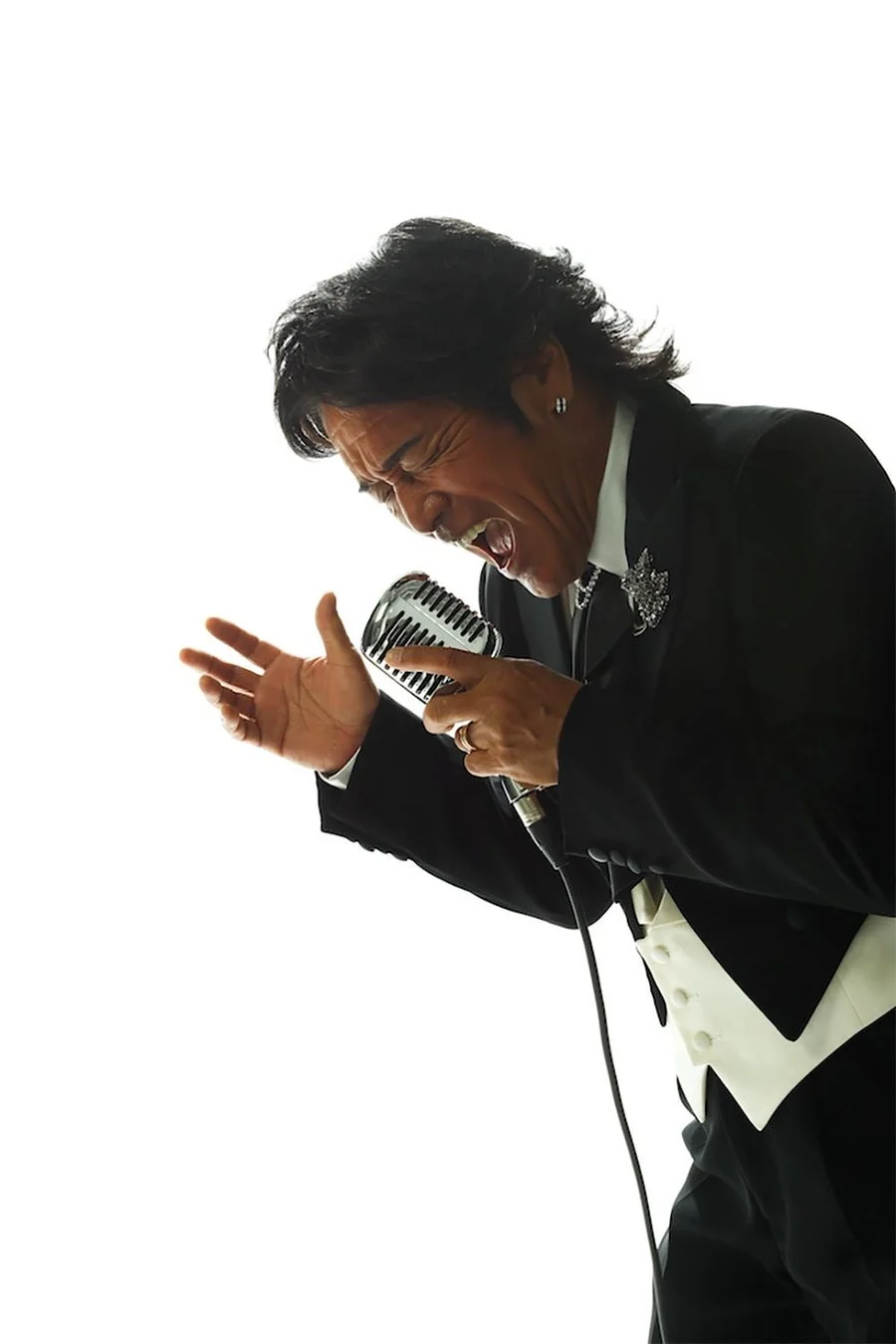 黒いタキシードを着て情熱的に歌う松崎しげる