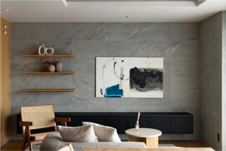 グレーのタイル壁に抽象画が飾られたモダンなリビングルーム