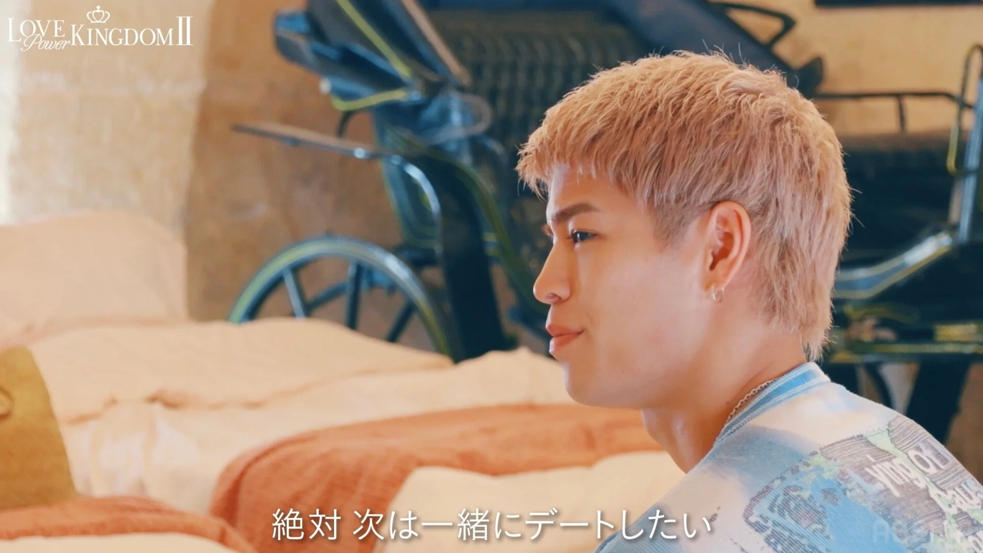 金髪の男性が真剣な表情で座っている様子