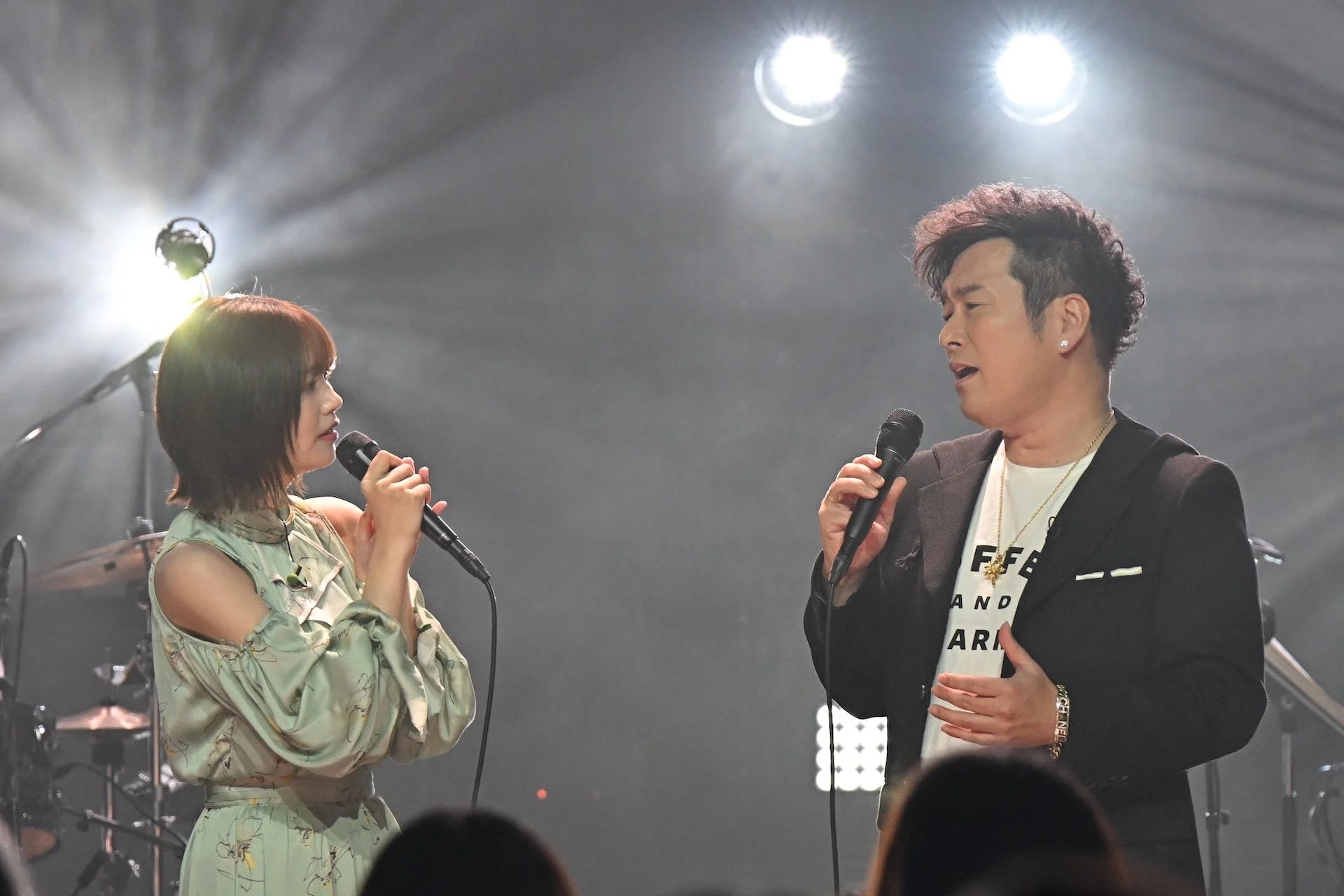 ステージ上でマイクを手に歌を披露する黒沢薫と中西アルノ