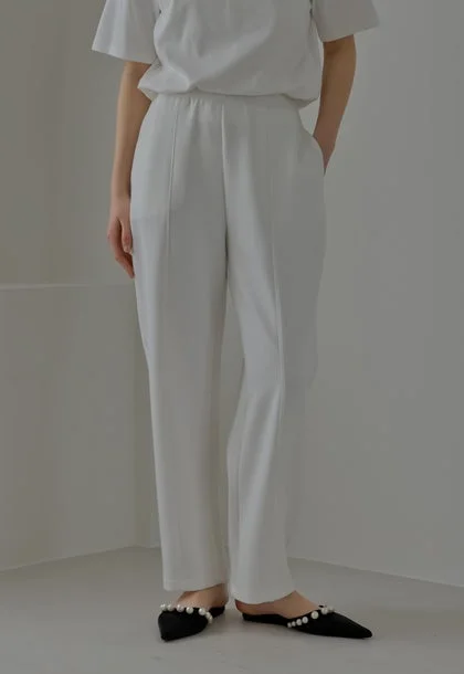 白Tシャツ、白パンツ、パール飾りのフラットシューズ