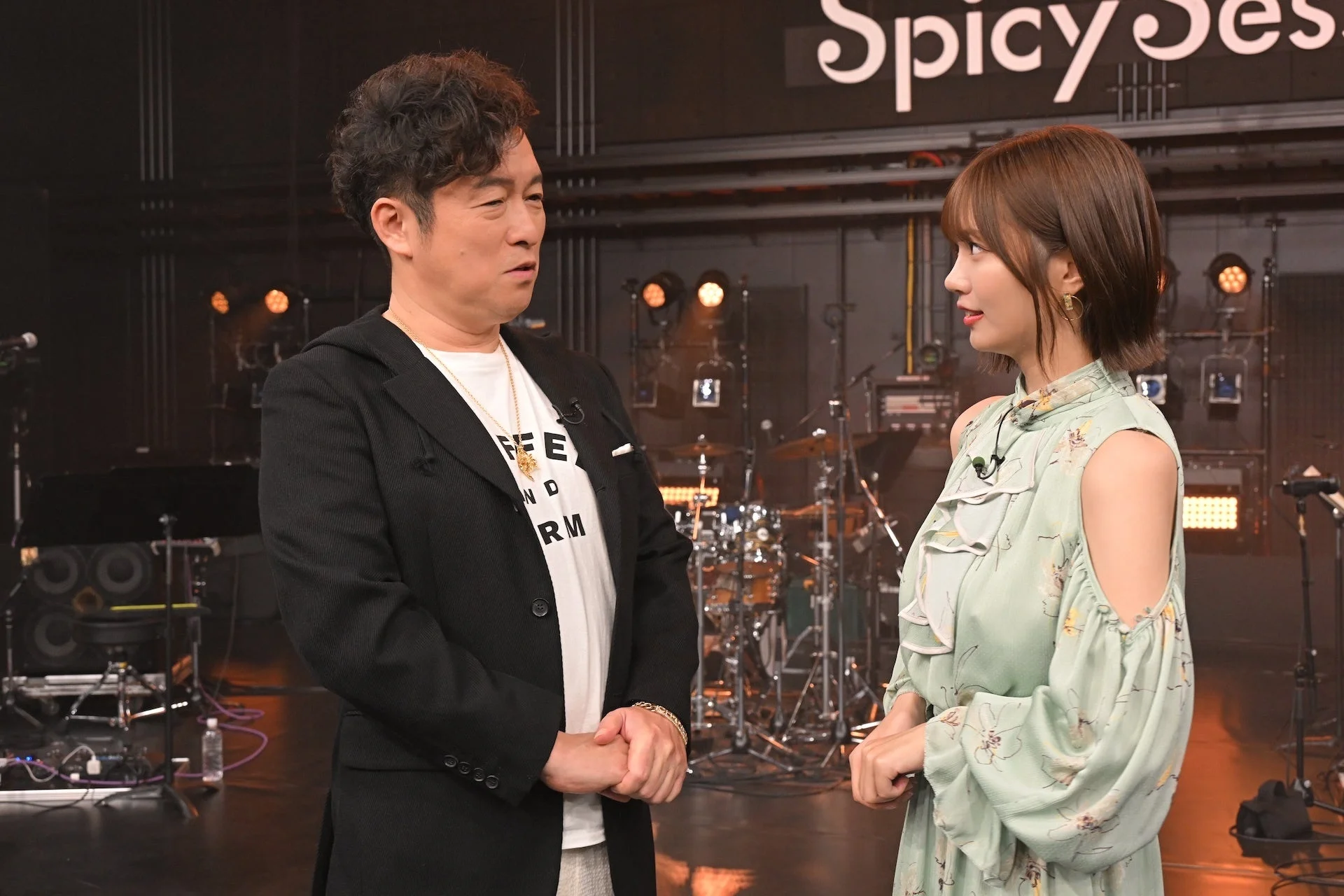 音楽スタジオのような場所で向かい合い話す黒沢薫と中西アルノ