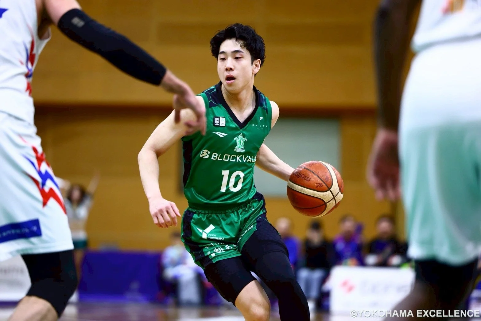 緑色のユニフォームを着たバスケットボール選手が、試合中にボールをドリブルしている