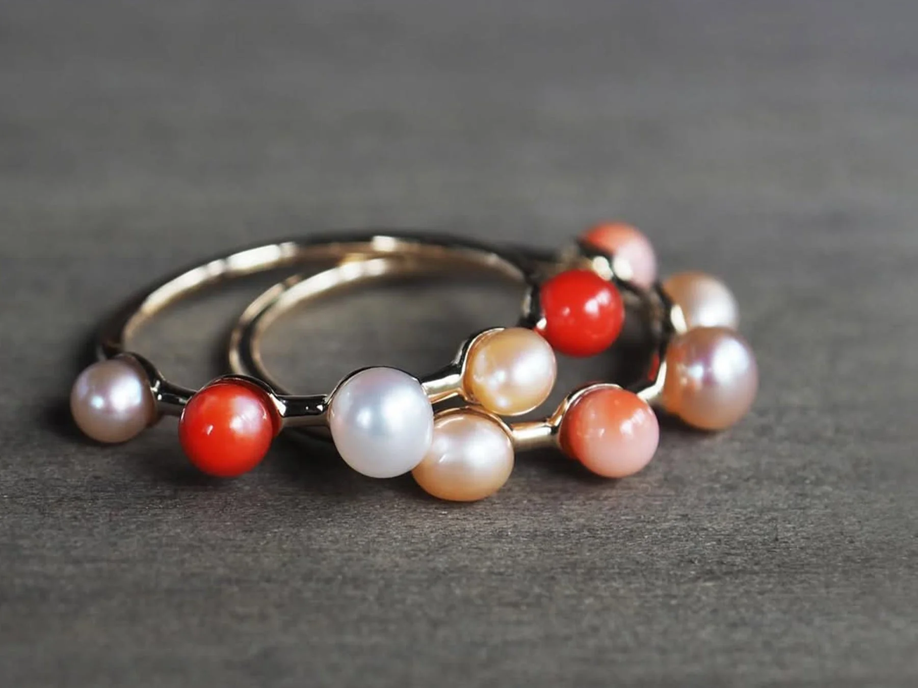 金色のリングに白、ピンク、赤、オレンジなど多色の真珠と珊瑚のビーズが連なったジュエリー