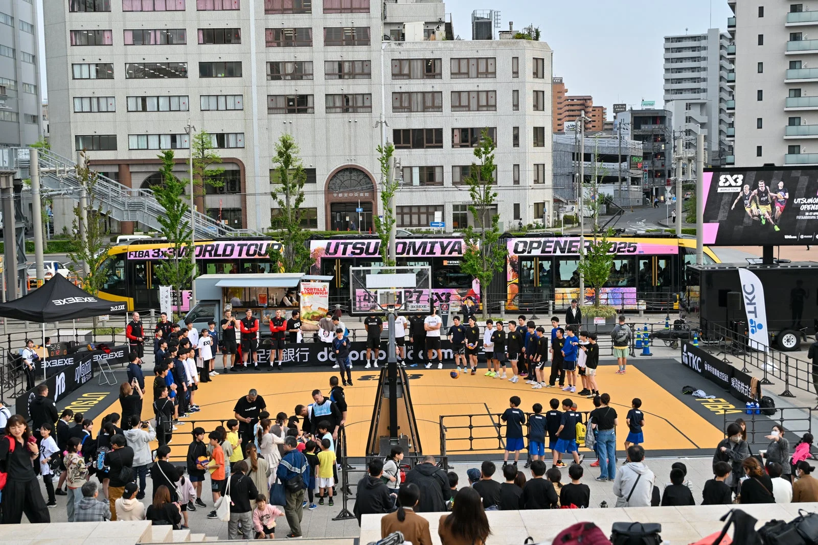 都市の中心部で3x3バスケットボールのイベントが開催されており、多くの選手と観客が集まっています