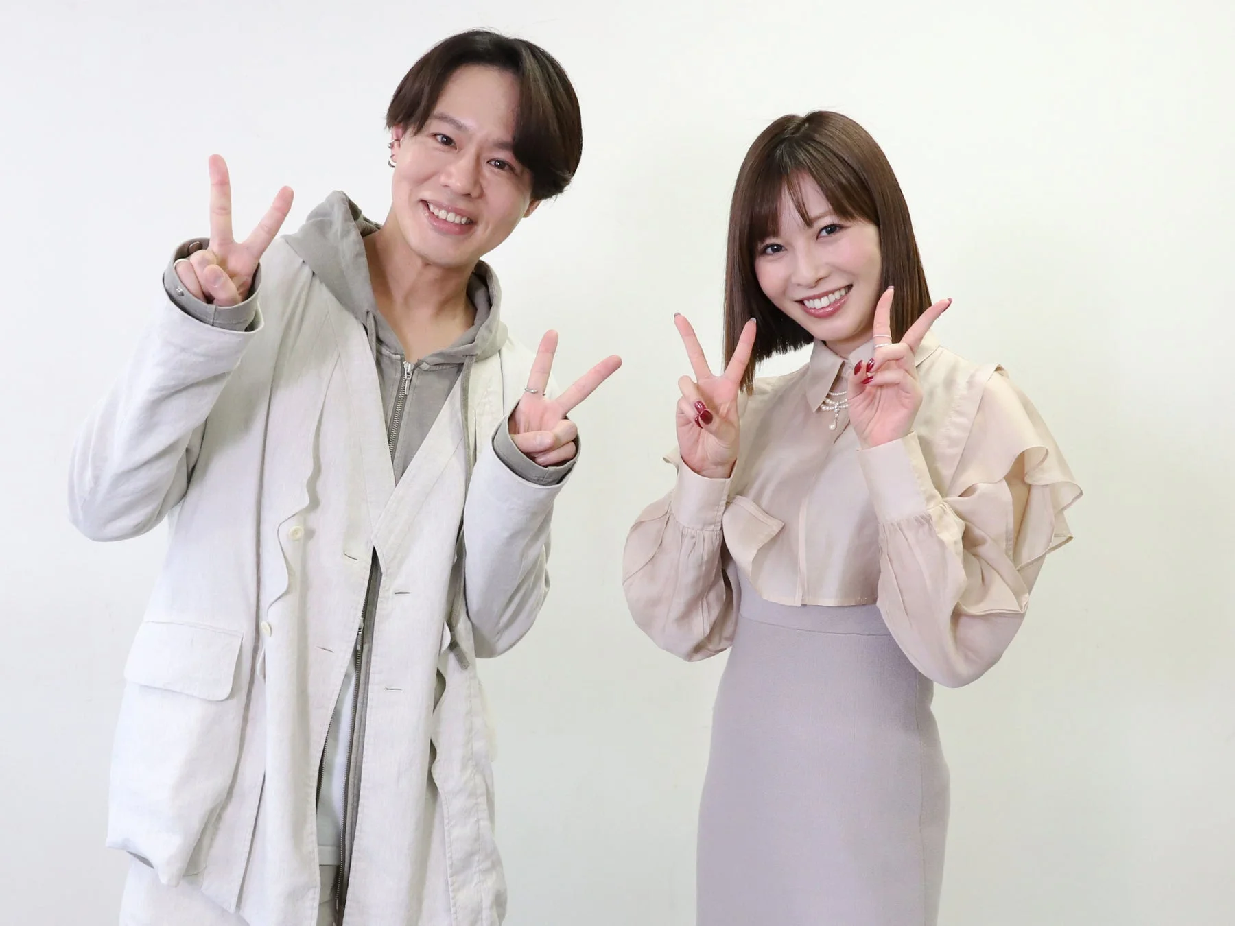 白い背景の前で笑顔でピースサインをする男女