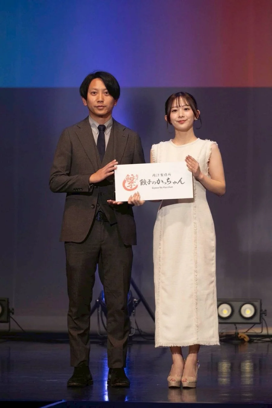 ステージで看板を持つ男性と女性