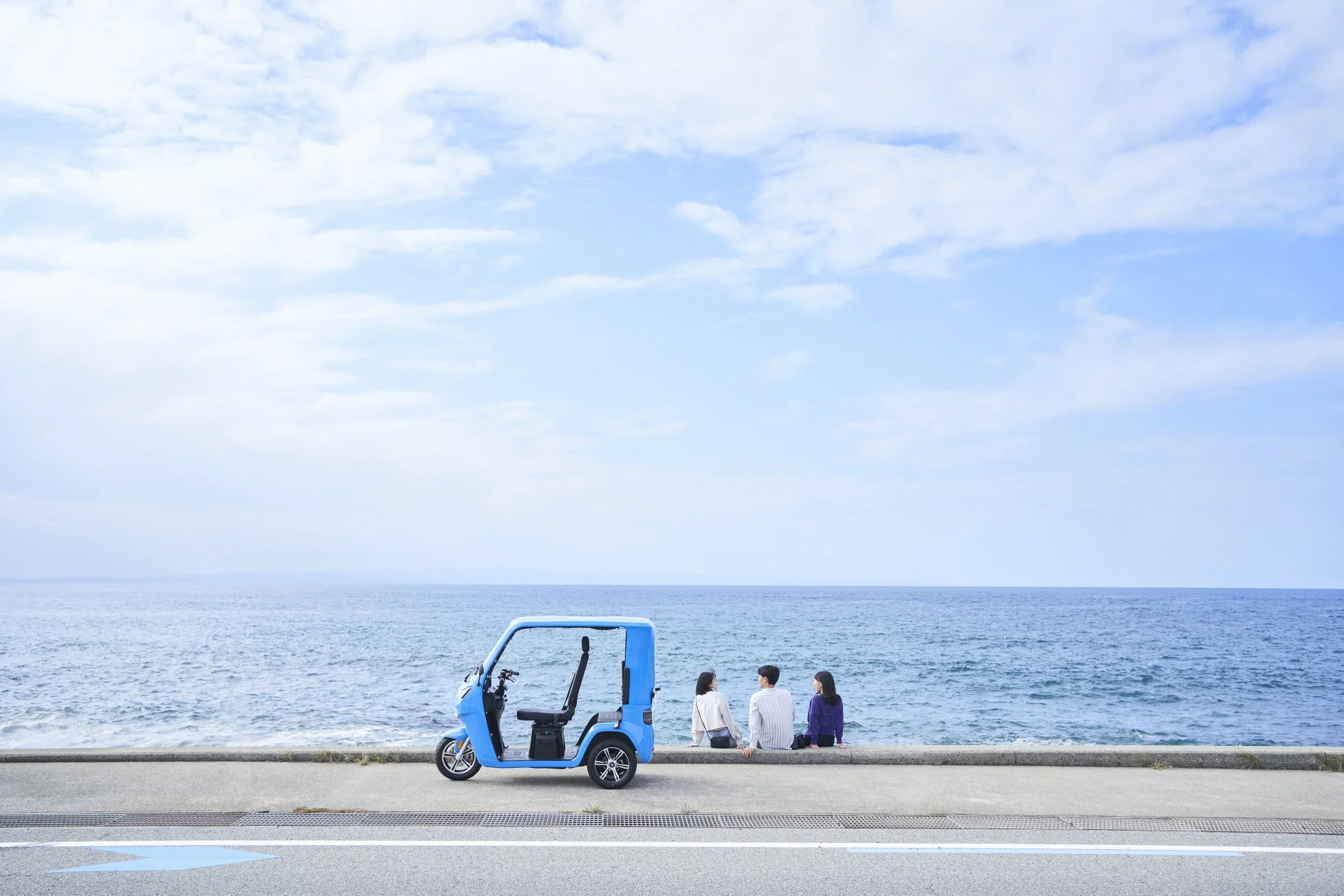 海辺に停車した電動車と人々