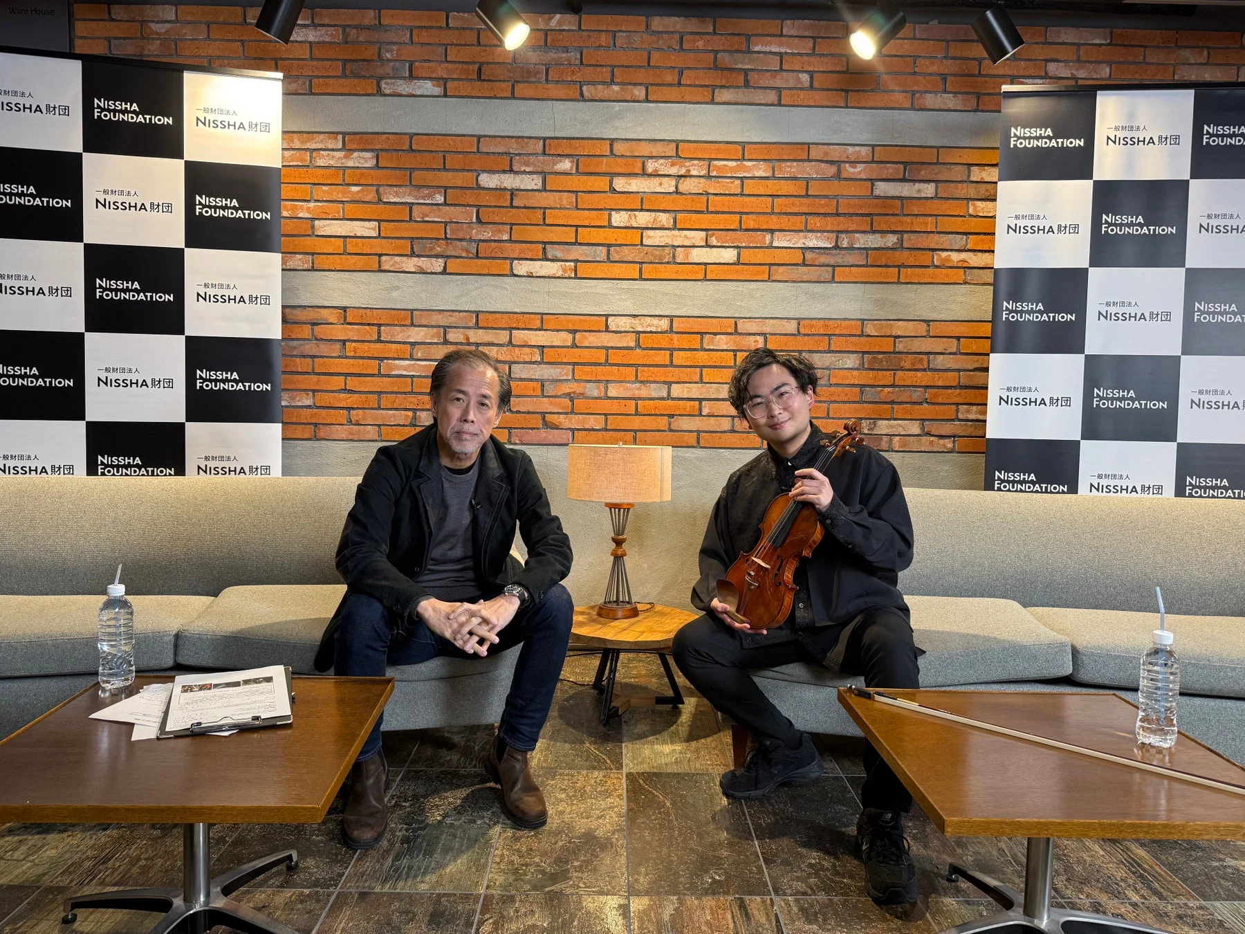 ヴァイオリンを抱える男性と対談する男性