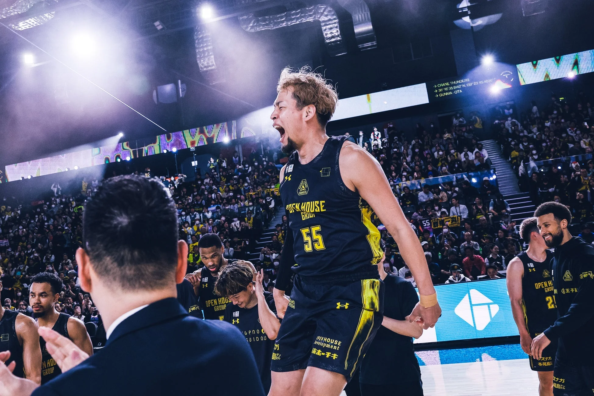 大勢の観客に囲まれたコートで力強く叫びながら感情を表現するバスケットボール選手