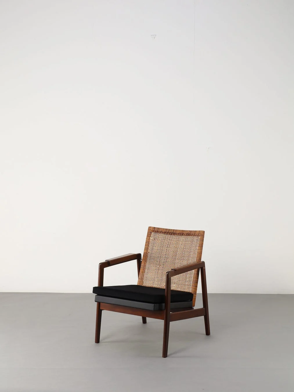 籐の背もたれと黒いクッションが特徴的な木製アームチェア