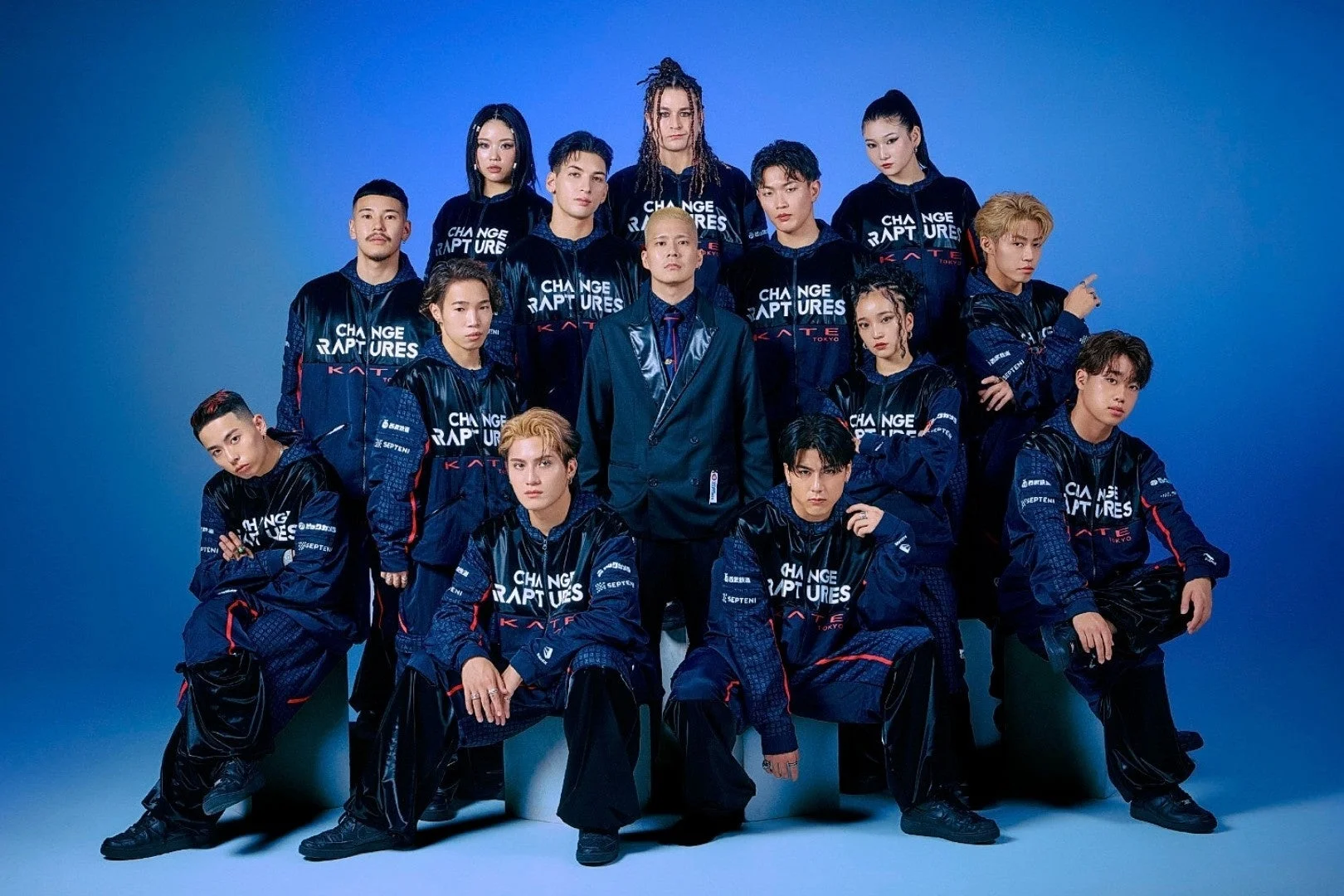 青い背景のスタジオで撮影された、多数の若い日本人男女のグループ写真