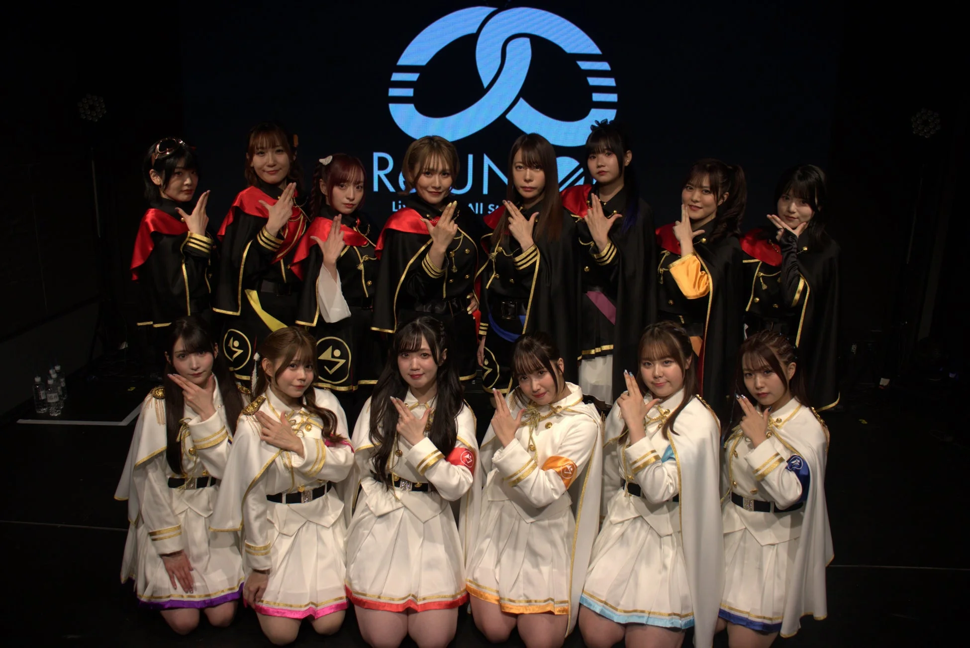 ステージでポーズをとるアイドルグループの集合写真