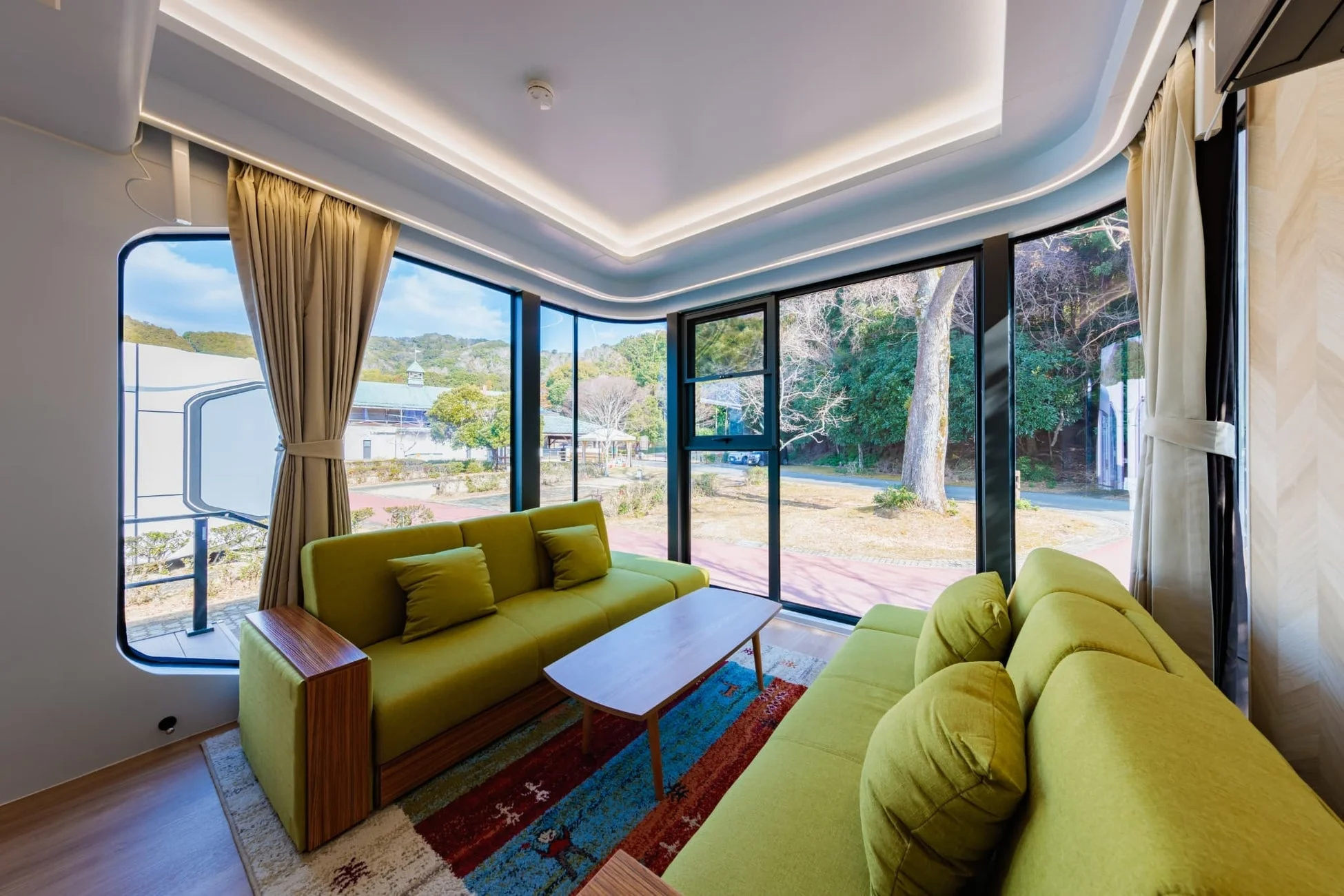 大きな窓から自然の景色が広がる、モダンで明るいリビングルーム