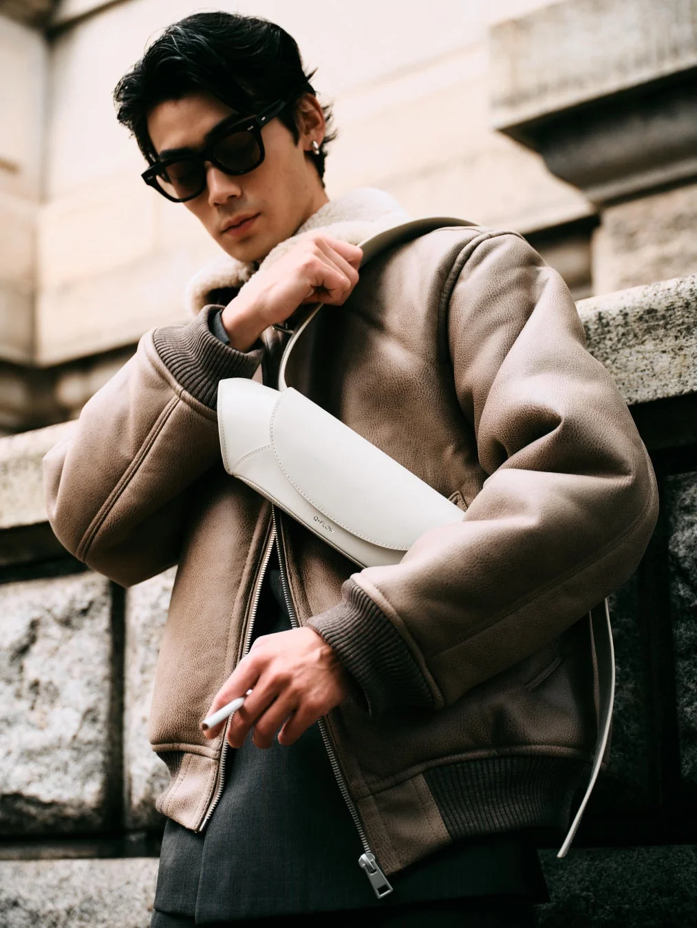 ボアジャケットと白いバッグを身につけた男性