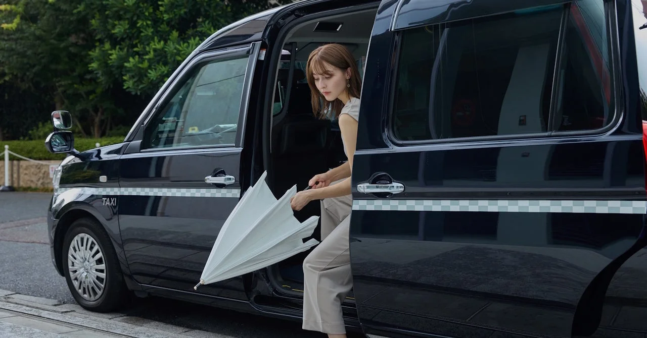 タクシーから降りる女性と傘