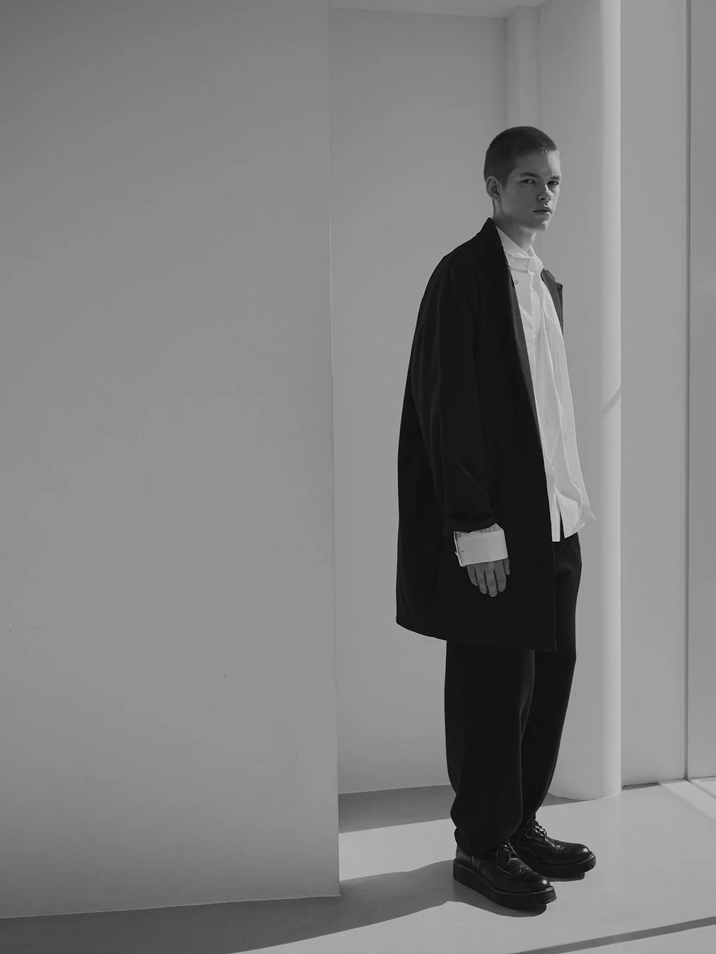 ルーズフィットの黒いアウターと白いシャツを着用した男性