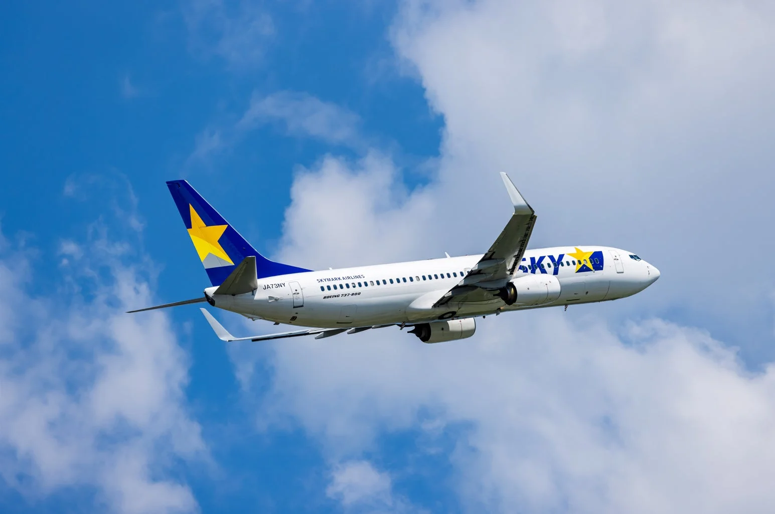 青い空と白い雲の中を飛行するスカイマーク航空のボーイング737-800型機です。