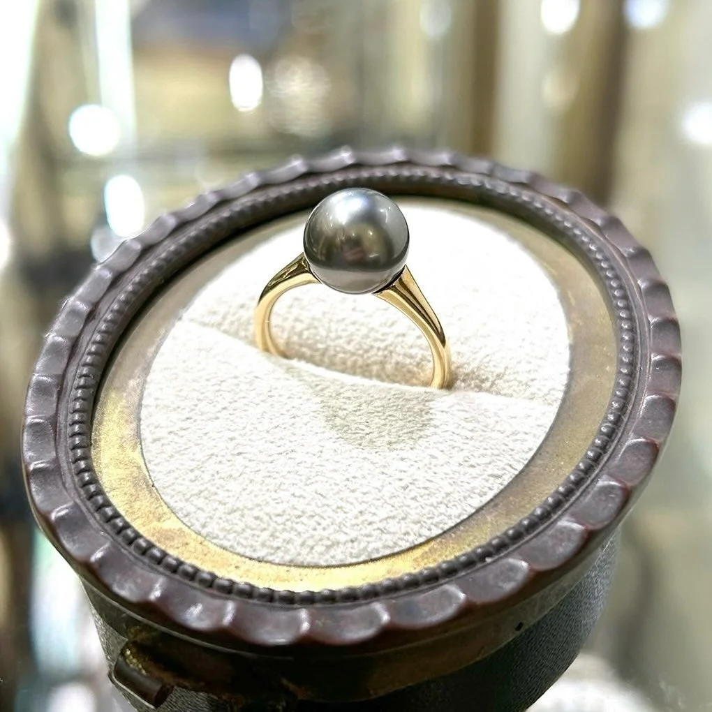 アンティーク調のリングボックスに収められた、大きな黒真珠があしらわれたゴールドの指輪