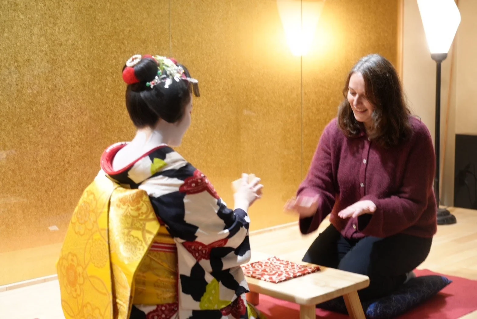 舞妓と西洋人女性が日本の伝統的な文化体験を楽しんでいる様子