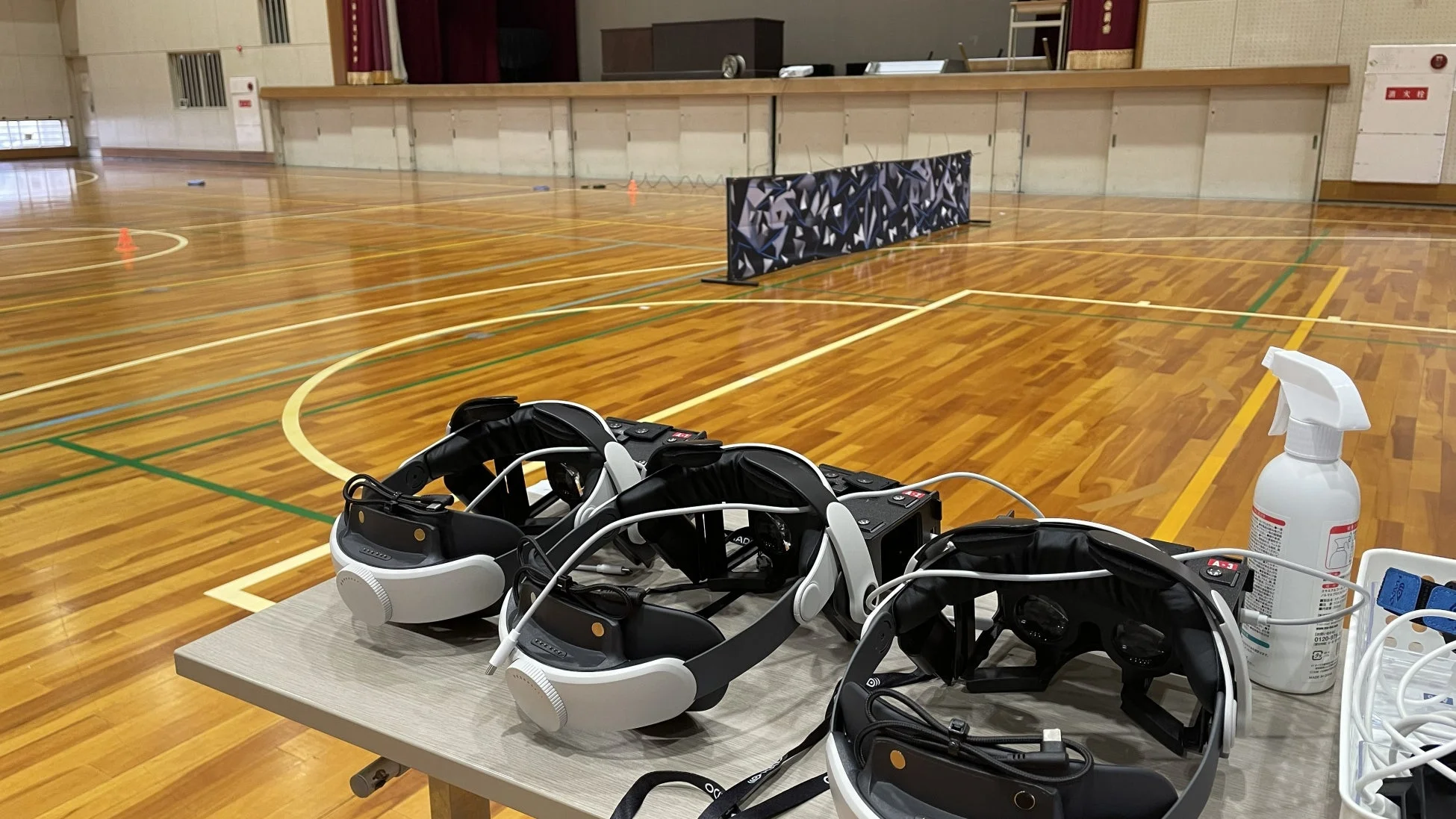体育館のコート脇にVRヘッドセットが並べられている様子