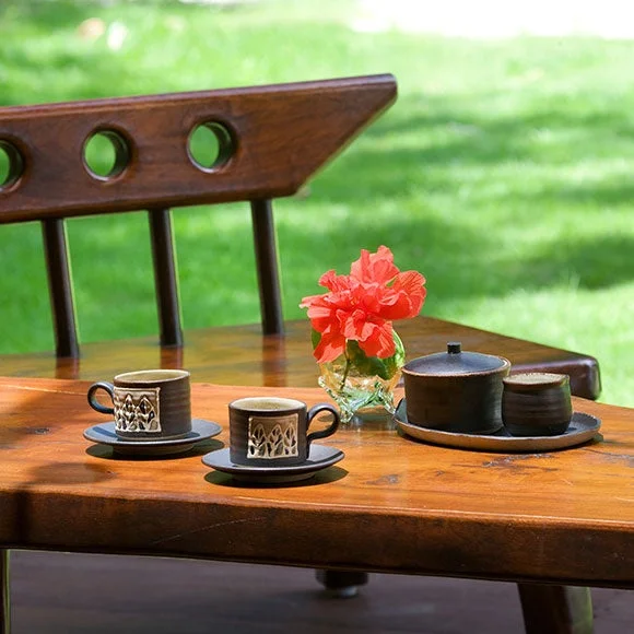 木製テーブルに置かれたコーヒーカップと赤い花