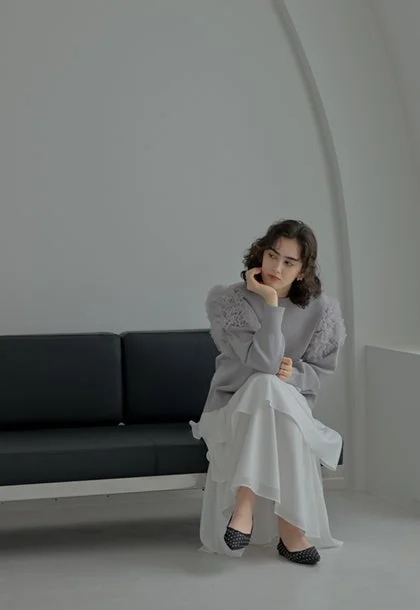 グレーふわふわ袖トップスと白いロングスカートのルック