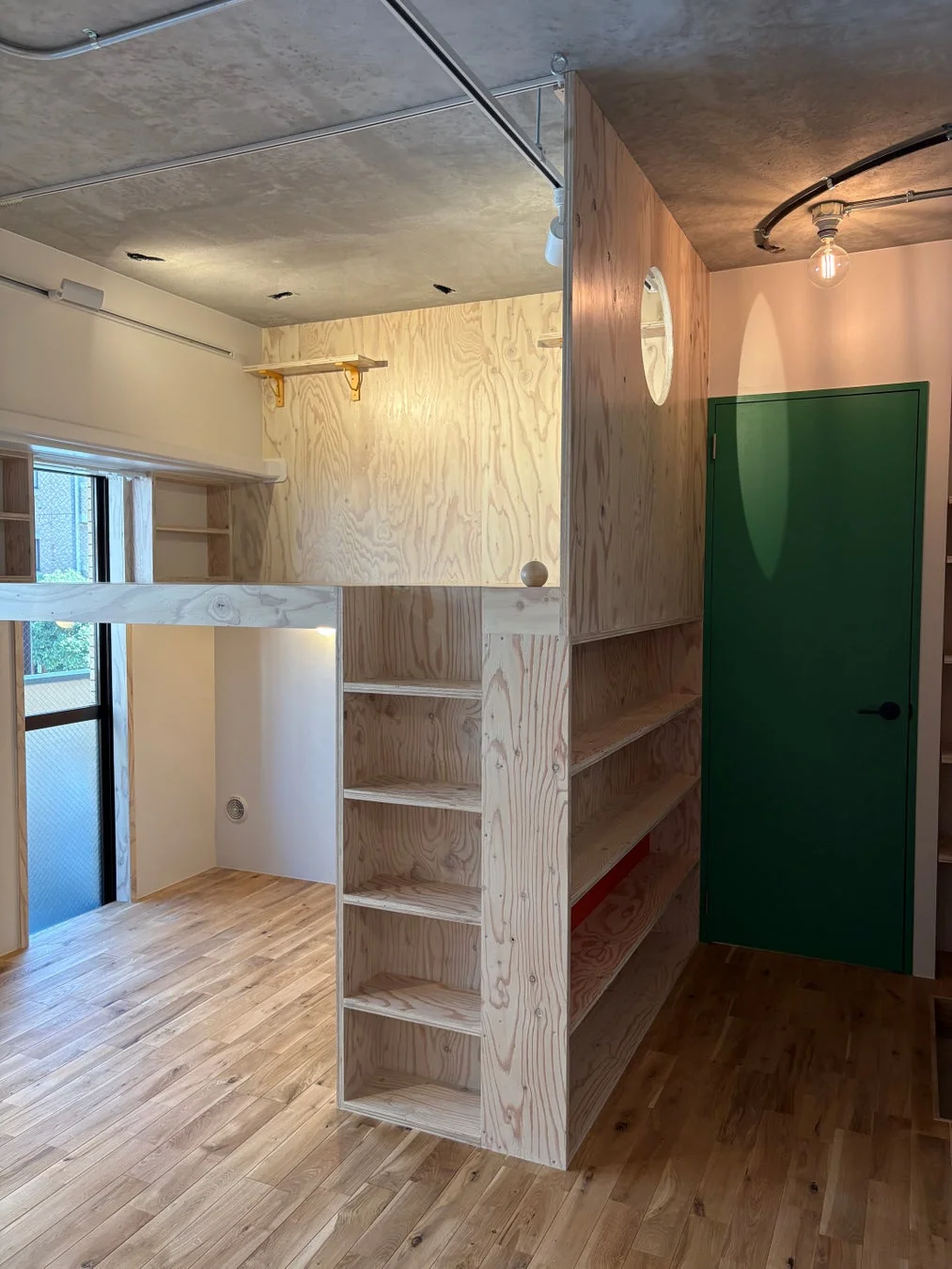 木製のロフトベッドと一体型になった本棚が特徴的な室内空間です。